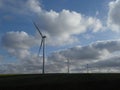 Row of five wind turbines surrounded by cottony clouds