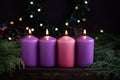 A row of four burning purple advent candles Christmas concept Royalty Free Stock Photo