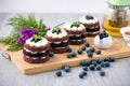 Row of four cocoa cakes with blue berry on top placing together violate flower, tea pot