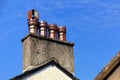 Row of four old ornate ceramic chimney pots on a rooftop chimney stack, with blue sky