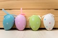 Row of Four Pastel Coloured Easter Eggs on Wooden Background