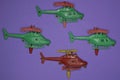 A row of four red green plastic toy models of helicopters