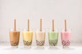 Row of fresh boba bubble tea glasses with straw on white background