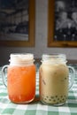 Row of fresh boba bubble tea glasses on wooden table with green plaid tablecloth background. Royalty Free Stock Photo