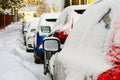 Row of fresh snow layer covered cars parked on the side of snow covered street Royalty Free Stock Photo