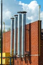 A row of galvanized steel chimney pipes on the facade of a brick boiler house building Royalty Free Stock Photo