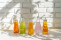 Row of glass bottles of different juices against white brick wall