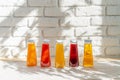 Row of glass bottles of different juices against white brick wall