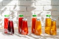Row of glass bottles of different juices against white brick wall