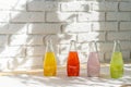 Row of glass bottles of different juices against white brick wall