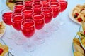 A row of glasses with red drinks, juice, champagne or wine at a party. Catering. Glassware on the table with a white tablecloth. Royalty Free Stock Photo