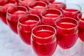 A row of glasses with red drinks, juice, champagne or wine at a party. Catering. Glassware on the table with a white tablecloth. Royalty Free Stock Photo