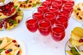 A row of glasses with red drinks, juice, champagne or wine at a party. Catering. Glassware on the table with a white tablecloth. Royalty Free Stock Photo