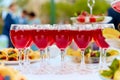 A row of glasses with red drinks, juice, champagne or wine at a party. Catering. Glassware on the table with a white tablecloth. Royalty Free Stock Photo