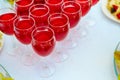 A row of glasses with red drinks, juice, champagne or wine at a party. Catering. Glassware on the table with a white tablecloth. Royalty Free Stock Photo