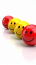 Row of glossy smiley face spheres, red and yellow, with soft lighting and reflection Royalty Free Stock Photo