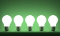 Row of glowing tungsten light bulbs on green