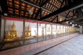 Row of golden Buddha images in earth touching mudra or subduing Mara pose, in cloister of Thai Buddhist temple Royalty Free Stock Photo