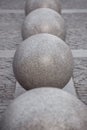 Row of granite balls on the pedestrian sidewalk paved with stone tiles.