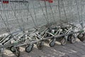 A row of gray shopping carts from a supermarket stand on the street