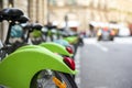 Row of green bikes for public rent stand at parking station on street in Paris ready for use Royalty Free Stock Photo