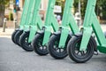 Row of green-blue electric scooters, a cleaner, modern alternative transportation option in cities. Close up on front wheels