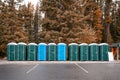 Row of green, blue portable chemical toilets in the forest at national park