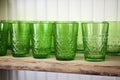 row of green glass tumblers on a shelf
