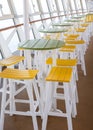 Row of green and yellow table and chairs bar arrangement on cruise deck Royalty Free Stock Photo