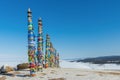 A row of high ritual cult pillars of the Buryats, tied with multi-colored ribbons, on a clear winter day. Sacred Cape Burkhan,