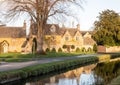 Row of historic quintessential Cotswold cottages by a river in Cotswolds, England