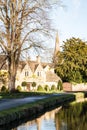 Row of historic quintessential Cotswold cottages by a river in Cotswolds, England, vertical shot