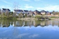 Row of homes along lakeshore with tree and cloud reflections across water surface Royalty Free Stock Photo