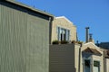 Row of houses with green flat modern design and beige or cream colored exterior visible chimney pipes and blue sky