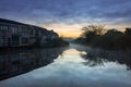 A row of houses surrounding a river filled with reflections of the houses at sunrise, Cape Town