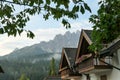A row of houses with the view on high and sharp Dolomites in Italy. There is a dense forest between the houses Royalty Free Stock Photo