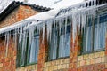 A row of icicles on the roof in the snow over the windows Royalty Free Stock Photo