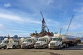 Row of Irving Oil trucks with oil rig in Halifax Harbour