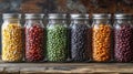 Row of jars filled with assorted colorful beans arranged on a wooden surface Royalty Free Stock Photo