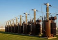 Large, brown electrical transformers is aligned on a grassy field under a Royalty Free Stock Photo