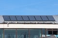 Row of large dark solar water heating panels mounted on top of old metal roof of local sports hall Royalty Free Stock Photo