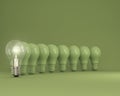 Row of light bulbs with glowing one different idea on green background