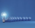 Row of light bulbs with glowing one different idea from the others on blue background Royalty Free Stock Photo