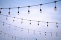 A row of light bulbs hanging on a wire on a bright sky background Royalty Free Stock Photo