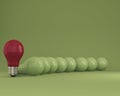 Row of light bulbs red one different idea from the others on green background Royalty Free Stock Photo