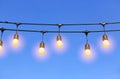 Row of light bulbs turned on over evening sky background Royalty Free Stock Photo