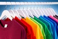 Row of many fresh new fabric cotton t-shirts in colorful rainbow colors hangng on clothes rail in wrdrobe. Various colored shirts