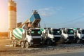 Row of many modern big mixer trucks parked against mobile temporary concrete plant factory at new asphalt road Royalty Free Stock Photo