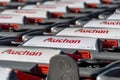 Row of many shopping carts branded with the logo of Auchan Royalty Free Stock Photo