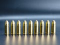 Row of 9 mm pistol bullets on dark background